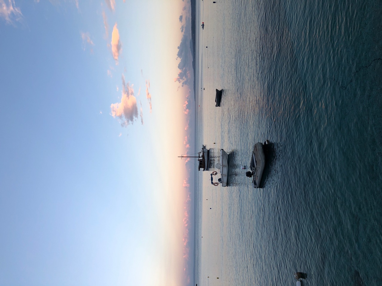 Agios Nikolaos harbour at dusk with boats on still water and pink sky