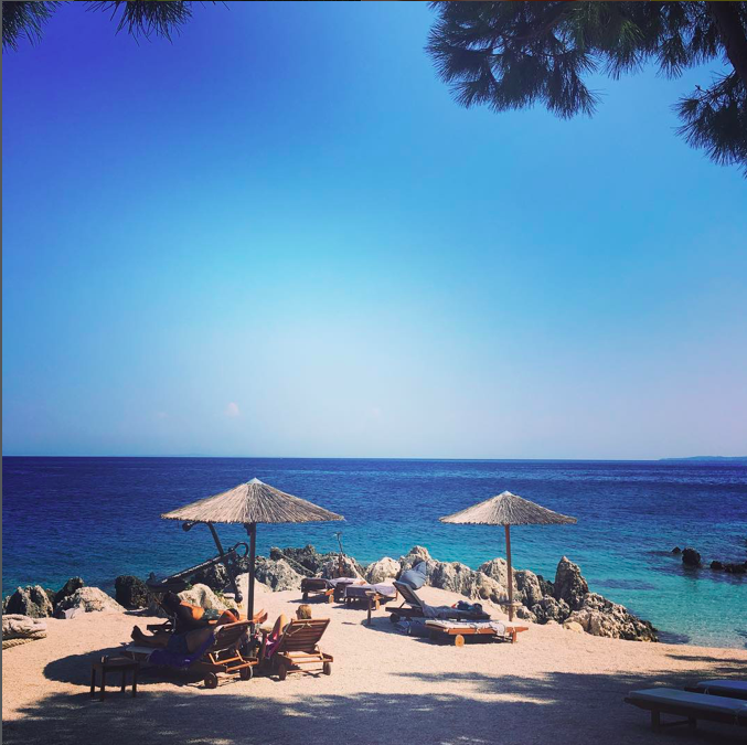 Nobelos beach with straw parasols and sun loungers facing the turquoise sea