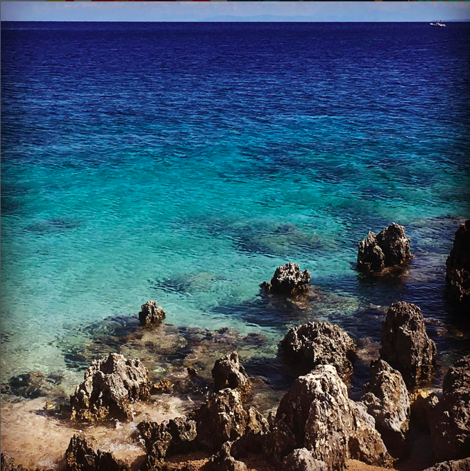Rocky coastline with electric blue water near the Blue Caves