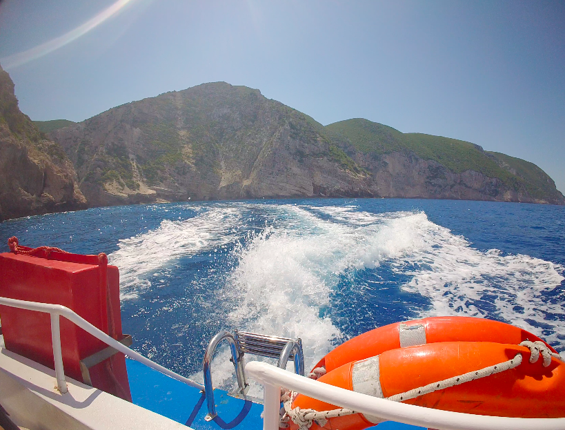 View from the back of a boat heading towards dramatic cliffs near Navagio