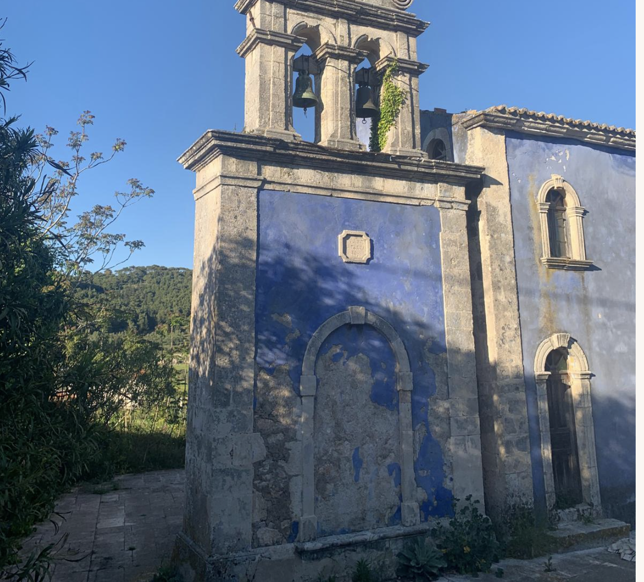 St Spyridon Church with blue painted walls and stone bell tower in lower Volimes